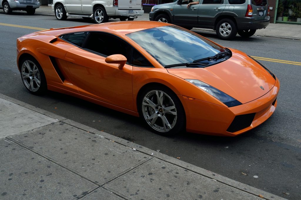 orange Lamborghini Gallardo parked on the side of a city street.