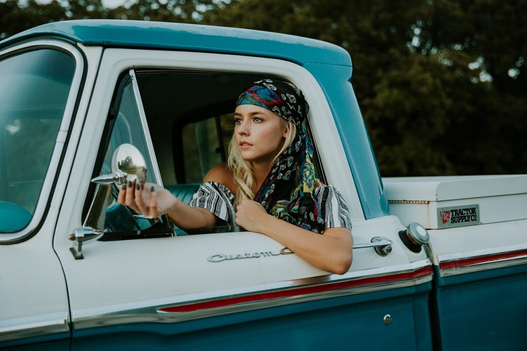 woman sitting in the driver’s seat of a vintage blue and white pickup truck