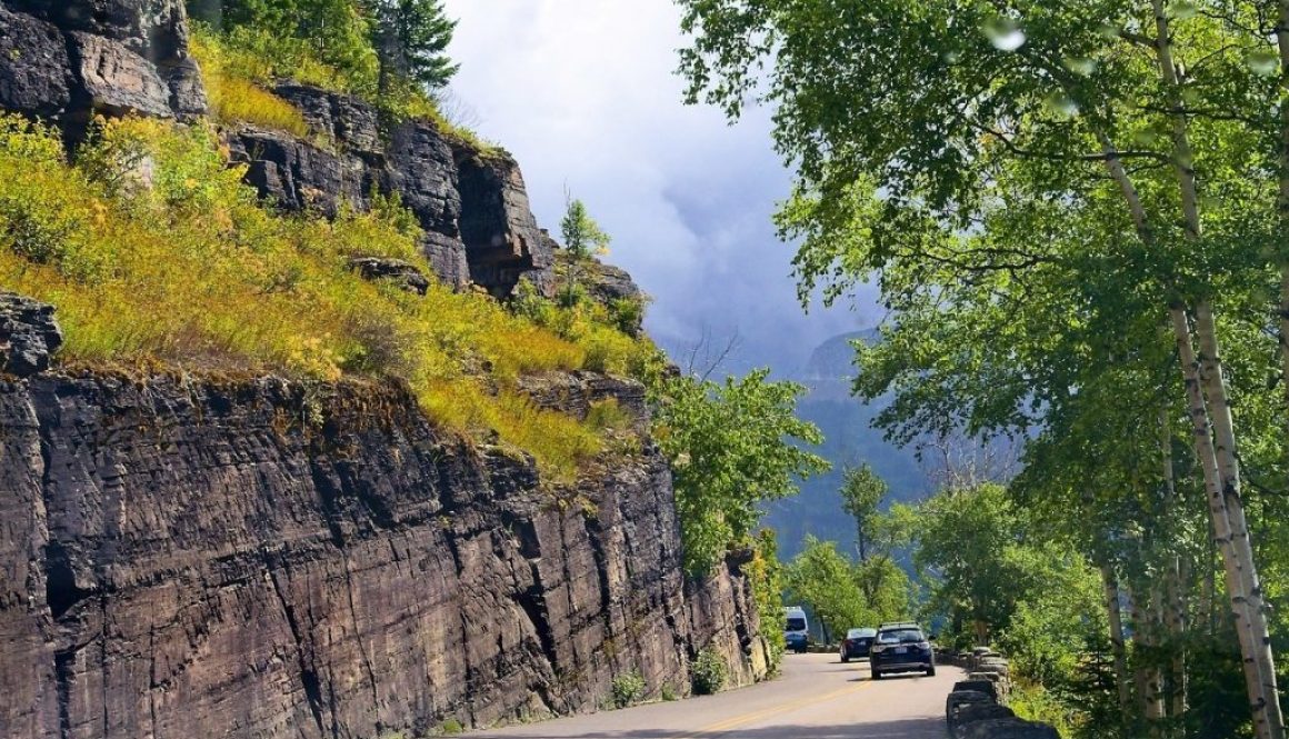 Cars drive along a winding mountain road in Montana, showcasing scenic beauty ideal for those completing a Montana car title transfer.