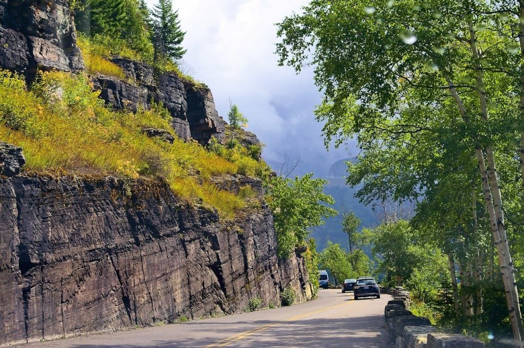 Cars drive along a winding mountain road in Montana, showcasing scenic beauty ideal for those completing a Montana car title transfer.