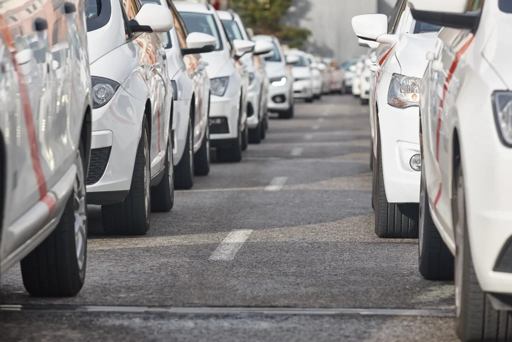A uniform fleet of white vehicles is parked bumper-to-bumper along both sides of a city street, stretching into the distance in an organized line.