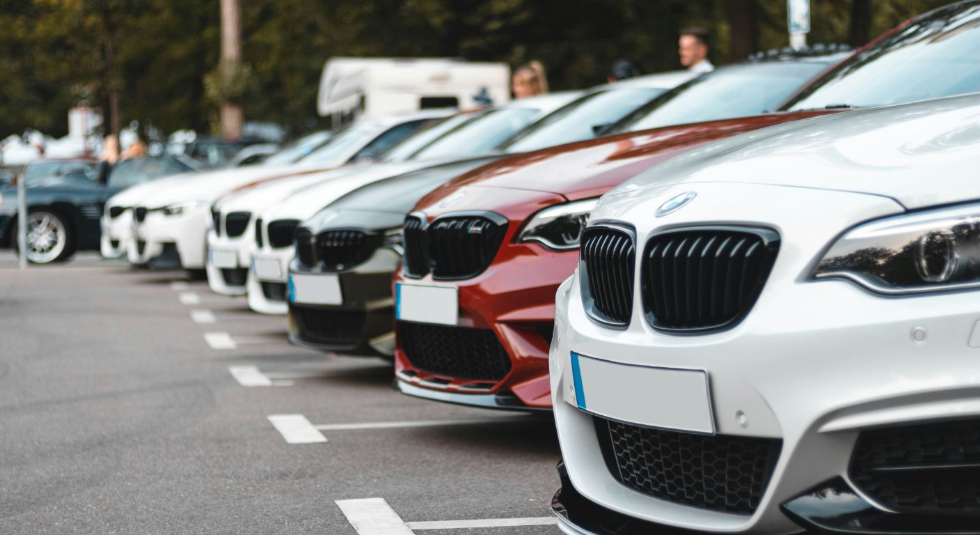 A lineup of BMW vehicles parked side by side, highlighting sleek front grilles and a range of colors in a dealership setting.