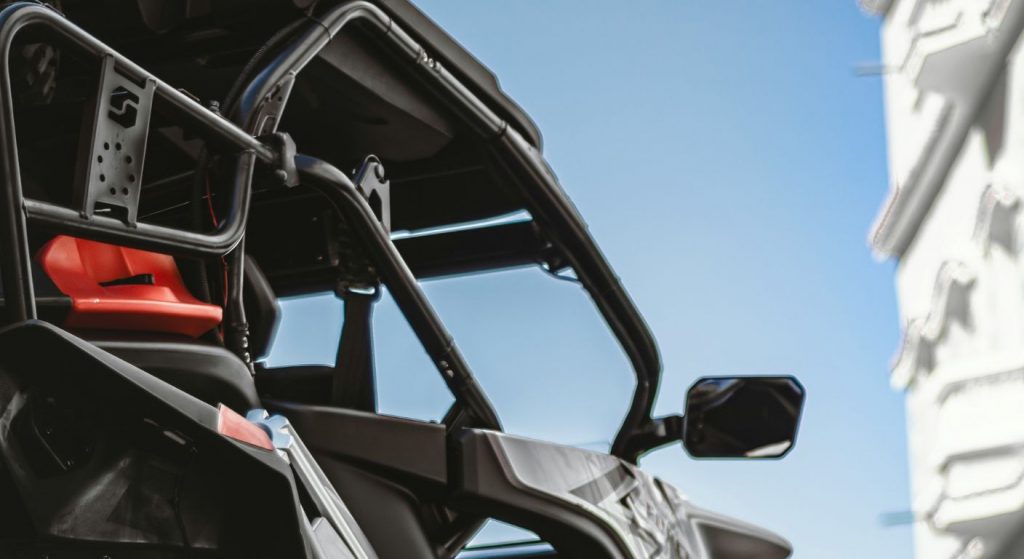 Close-up of a side-by-side UTV with roll cage and red seat under a clear blue sky